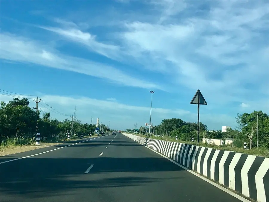 Four-lane Tamil Nadu state highway with a divider under a blue sky